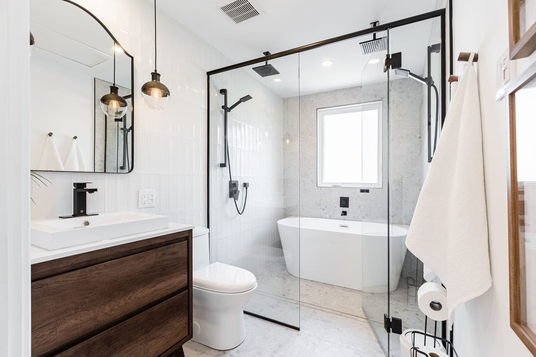 Salle de bain moderne avec meuble en bois, douche vitrée et baignoire îlot blanche élégante.